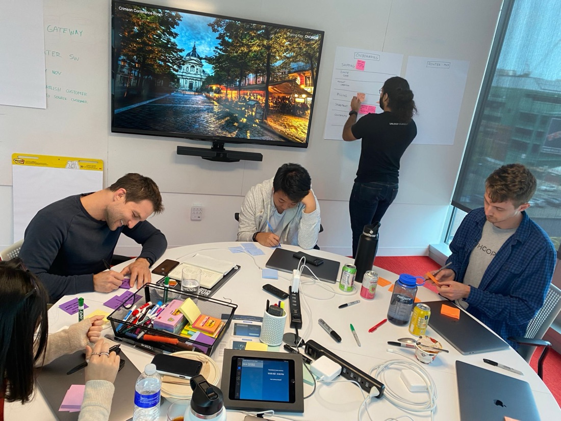A team mapping onboarding, billing and storefront ideas on sticky notes around a conference table