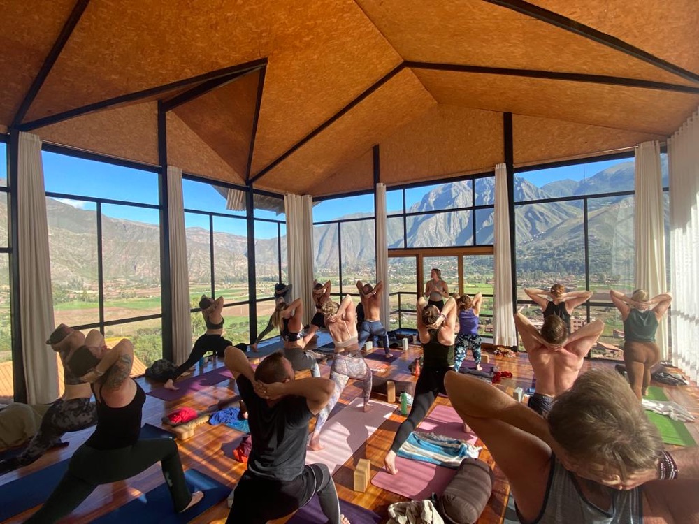 A yoga class at a retreat in Peru, in a glass-walled studio facing green mountains