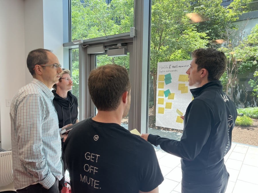 Teammates gathered at a whiteboard, adding ideas