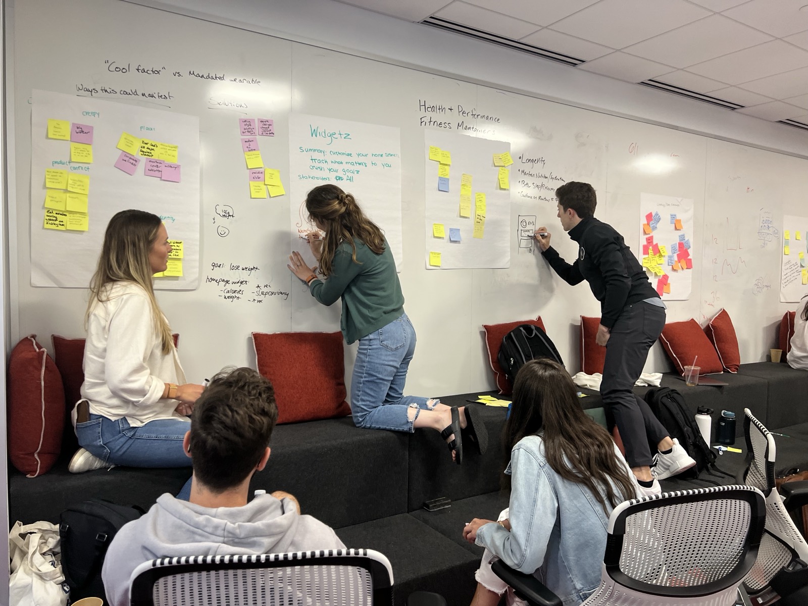 Teammates sketching on whiteboards covered in sticky notes during a WHOOP workshop